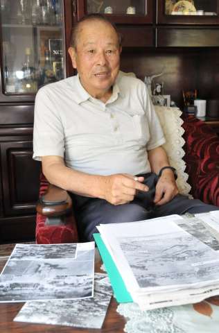 実家周辺が爆撃された当時の写真など見ながら体験を語る木原武晴さん＝姶良市加治木町諏訪町