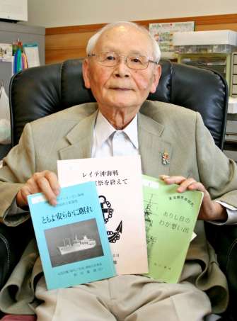 戦争の記録、記憶をつづった本と備忘録を手にする新川義雄さん＝上荒田町