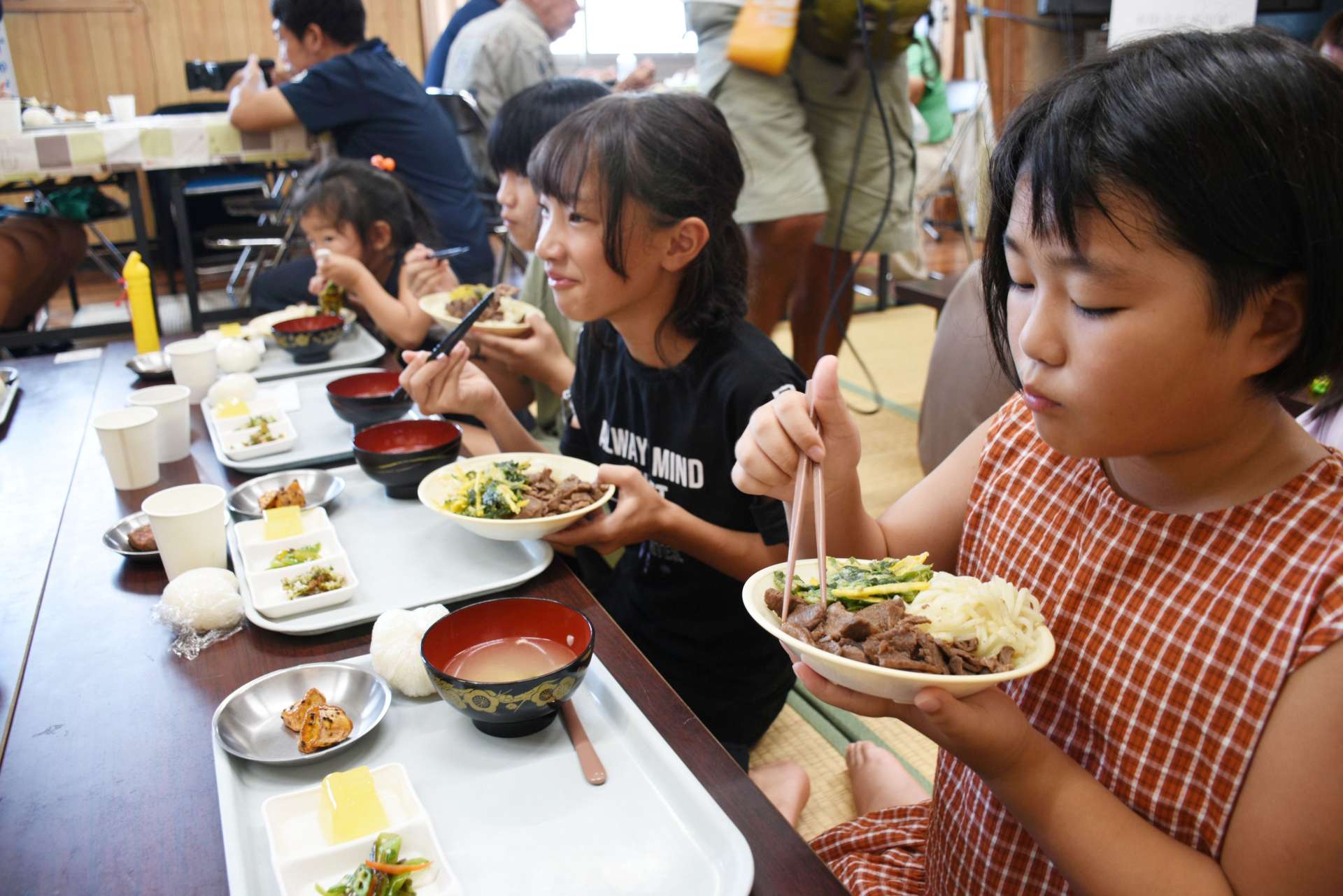 西之表市産の牛肉を使った肉うどんを食べる子どもたち＝同市西之表の美浜町自治公民館