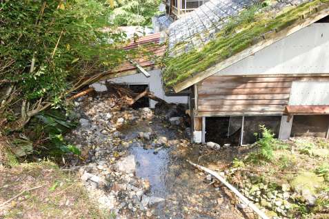 外から見た下の浴室（右）と脱衣所（左）。窓ガラスは割れ、川の水が流れ込む＝４日、出水市武本の湯川内温泉かじか荘