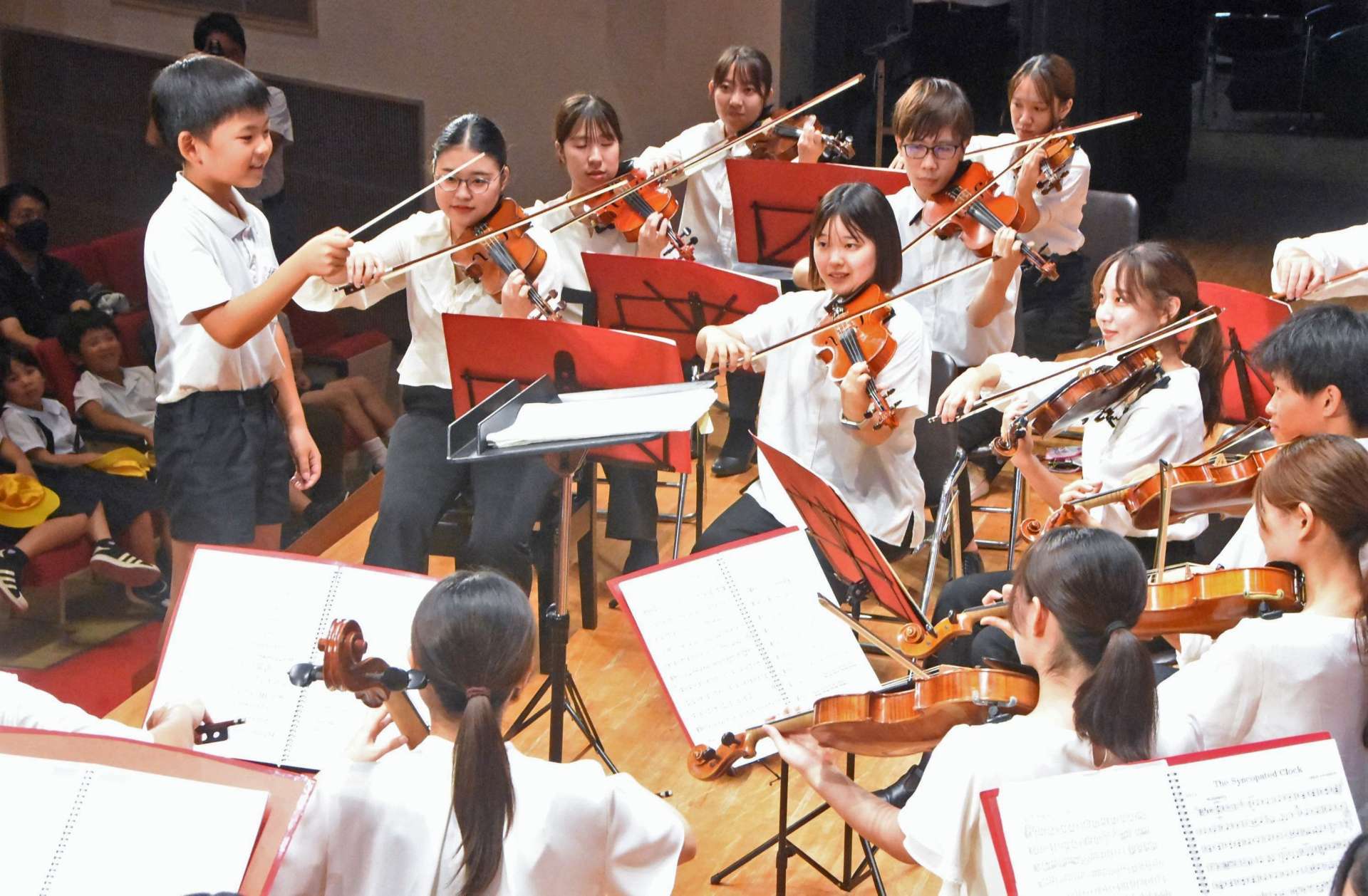 鹿大管弦楽団の演奏で指揮体験する児童（左）＝南さつま市の金峰文化センター