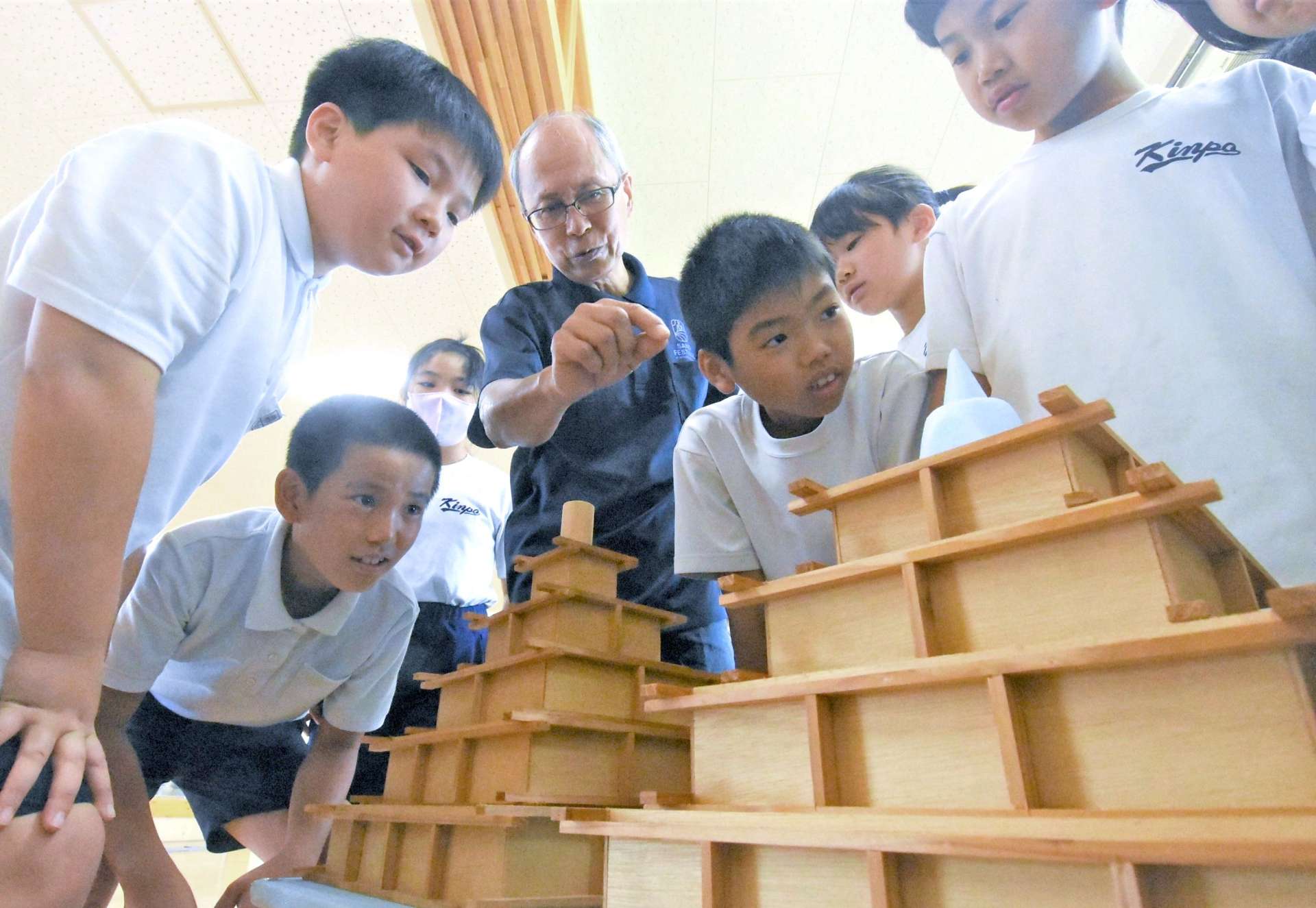 児童に砂像の作り方を説明する塩賀千弘さん（中央）＝南さつま市の金峰学園