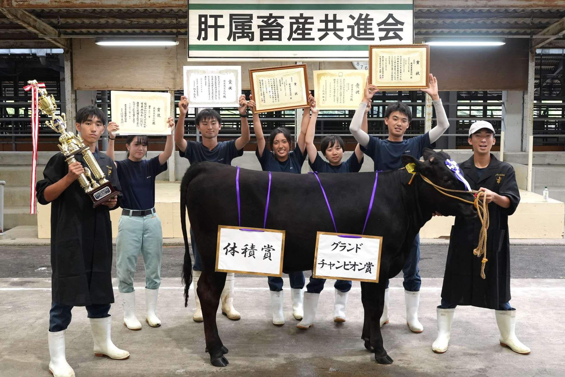 グランドチャンピオンに輝いた「あおい」号と鹿屋農業高校鹿児島黒牛研究部員＝１０日、鹿屋市の肝属中央家畜市場