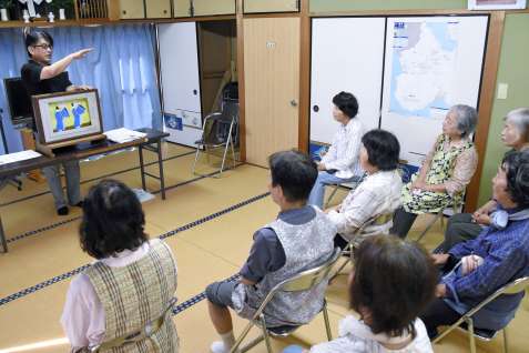 紙芝居を通し、地元住民に立て札刷新の趣旨を説明する石堂秀一さん＝指宿市開聞