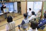 紙芝居を通し、地元住民に立て札刷新の趣旨を説明する石堂秀一さん＝指宿市開聞