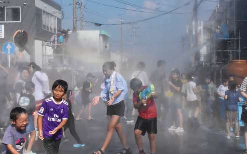 歩行者天国で温泉水を掛け合う来場者＝８日、阿久根市大丸町