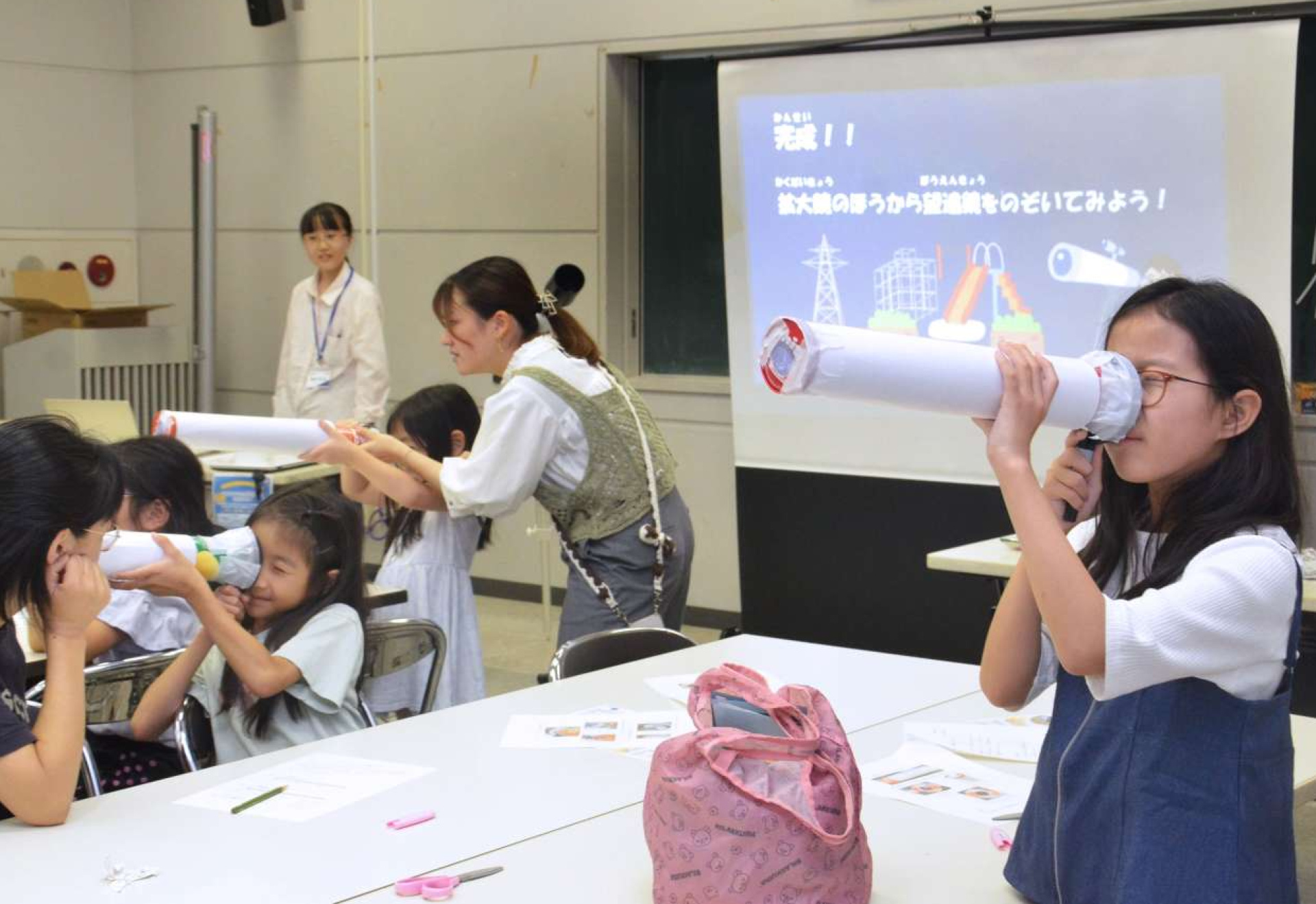 手作りの天体望遠鏡をのぞく子どもたち＝鹿児島市立科学館
