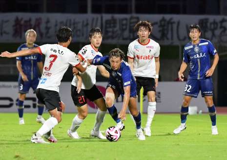 相手に囲まれながらボールをキープする鹿児島Ｕの有田稜＝鹿児島市の白波スタジアム