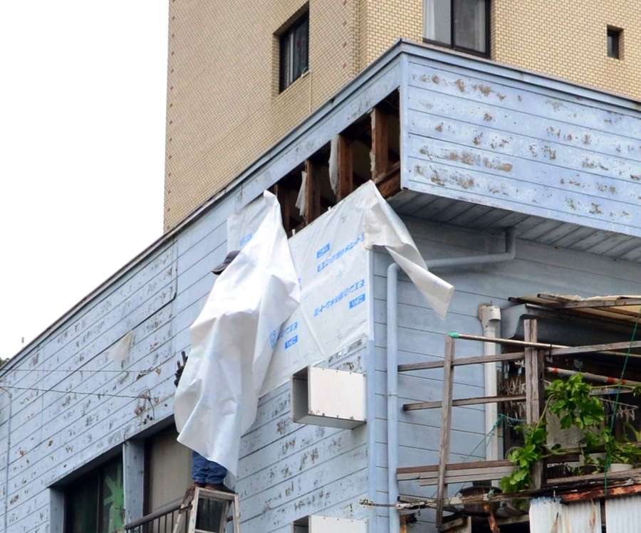 強風ではがれた住家の壁＝１５日、奄美市名瀬塩浜町