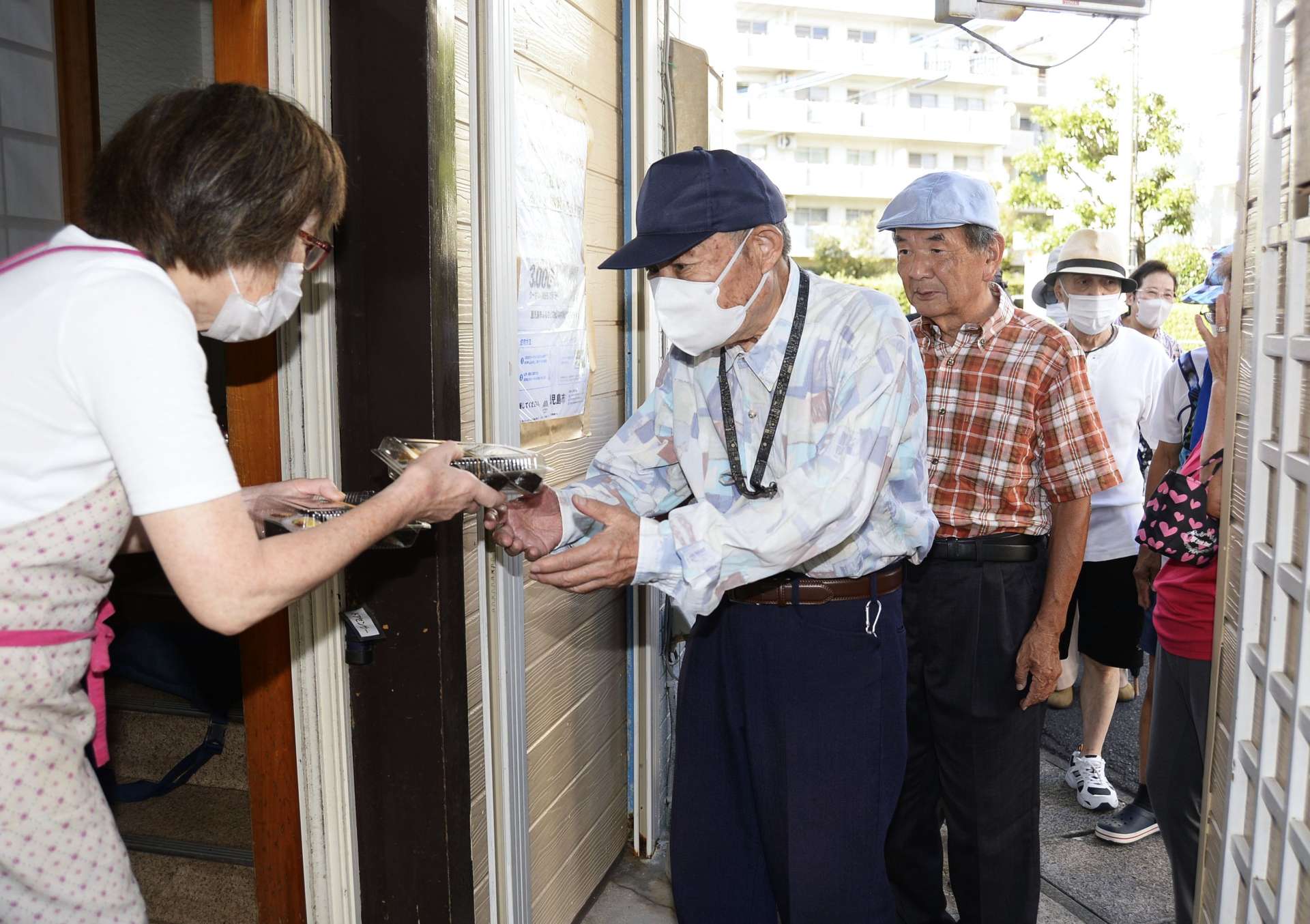 巻きずしを受け取る高齢者ら＝１６日、鹿児島市真砂本町の寿司孝