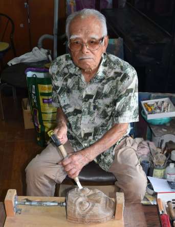 のみを使って仮面づくりに打ち込む新名威さん＝曽於市大隅町月野
