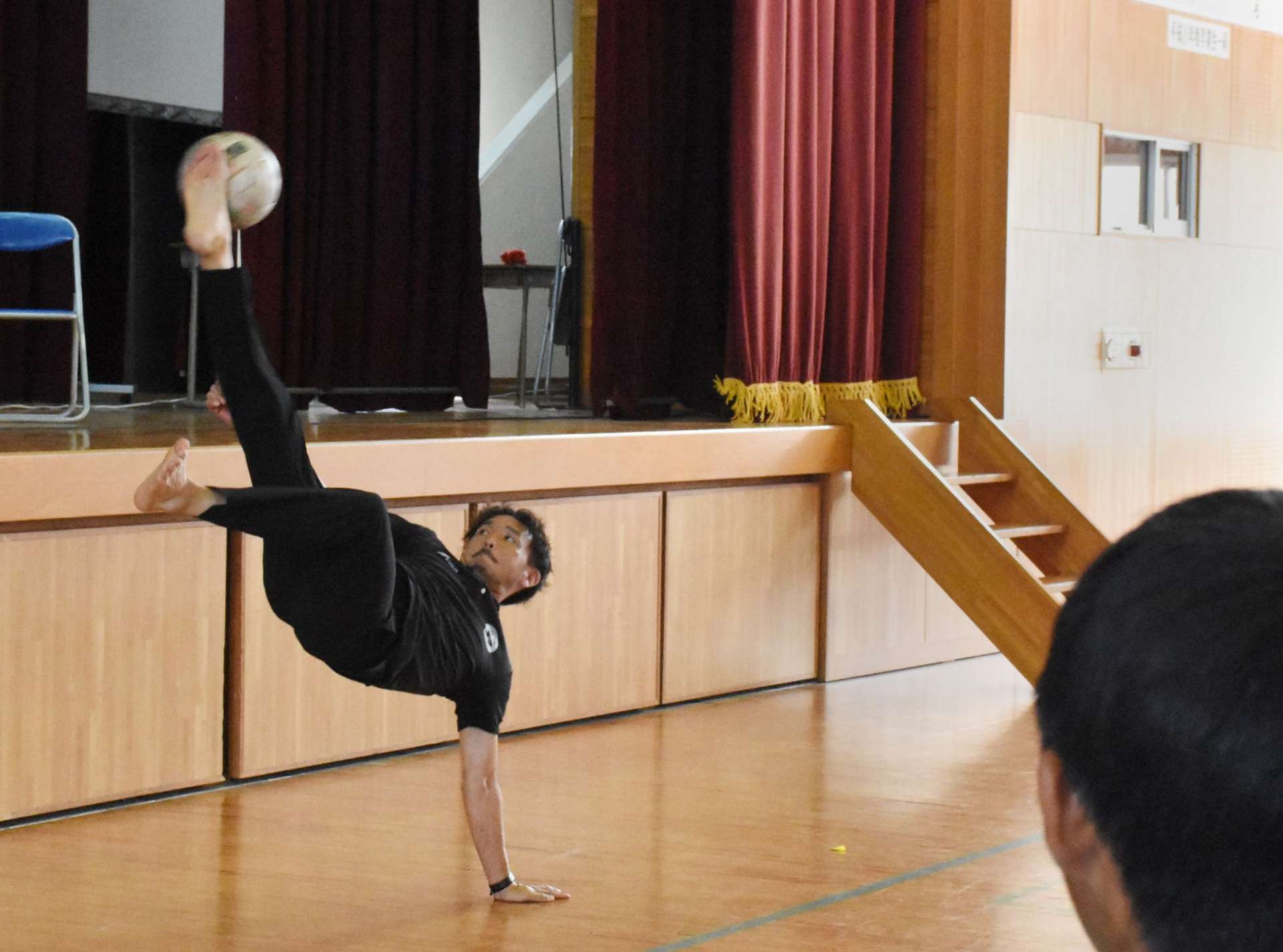 生徒の前でオーバーヘッドキックを披露する田上裕さん＝１４日、志布志市有明の有明中