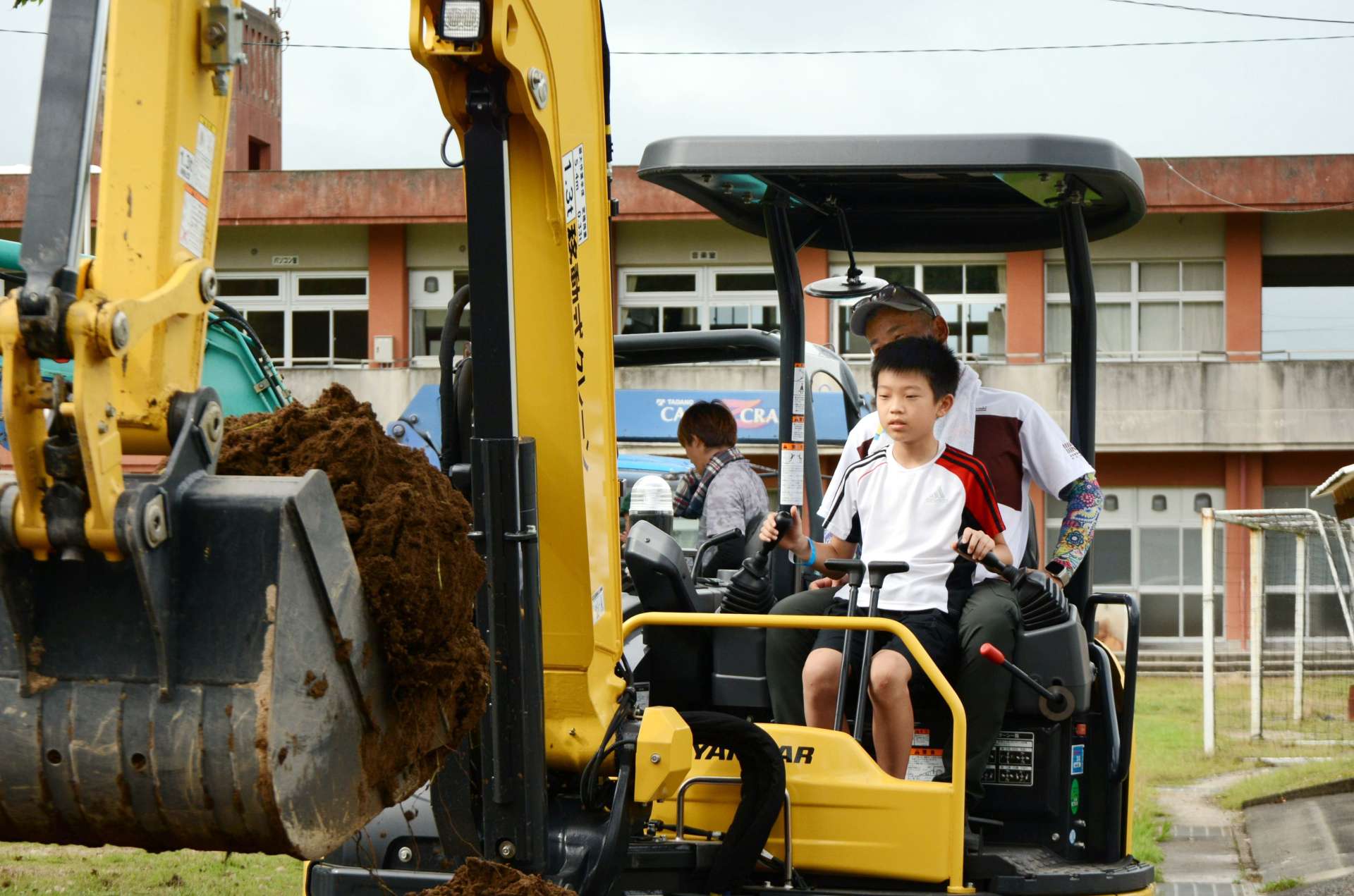 ショベルカーを操作する子どもたち＝１５日、さつま町白男川