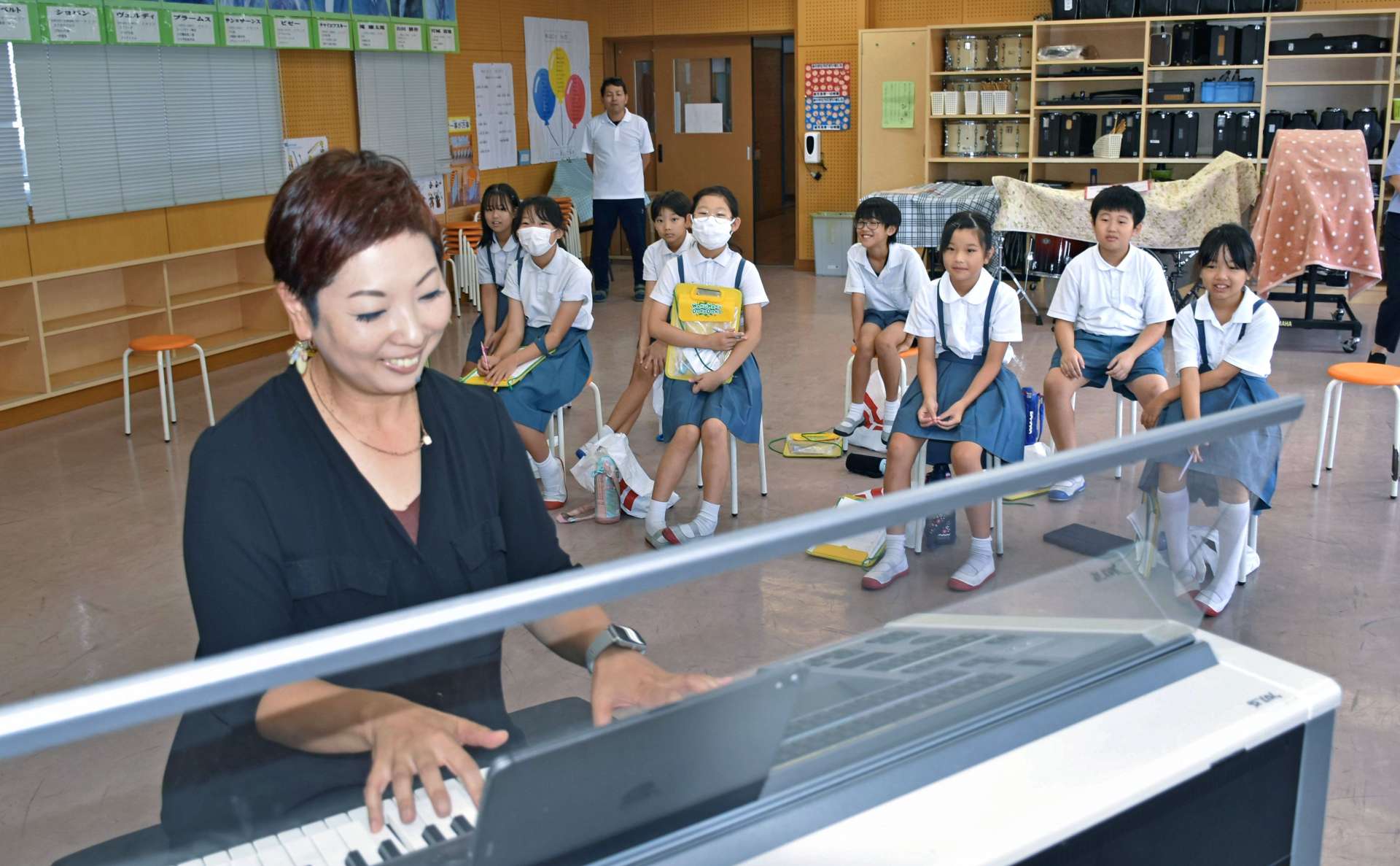 ピアノ教師から実演を交えて仕事の楽しさを学ぶ児童＝霧島市国分中央２丁目