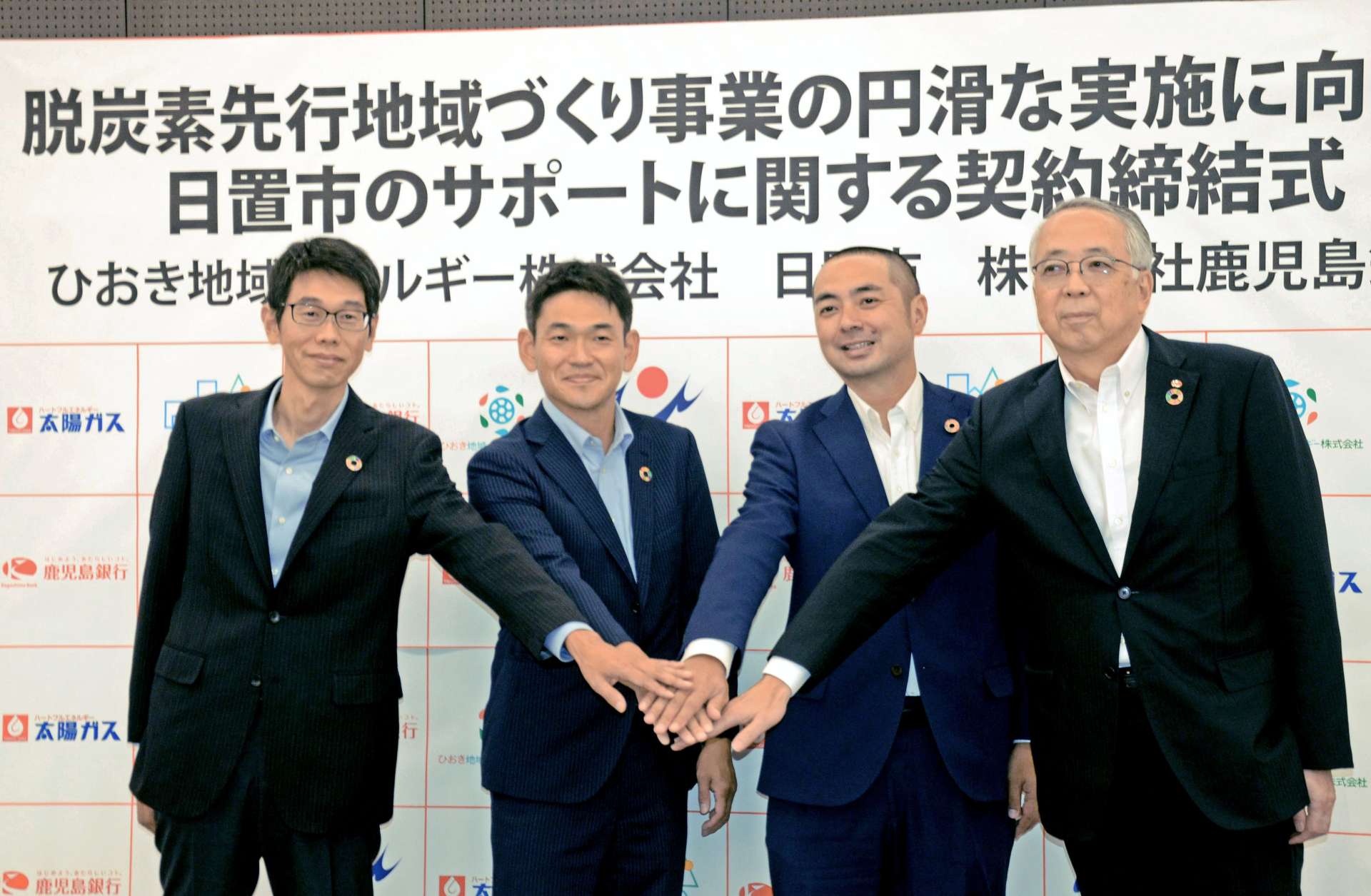 脱炭素社会の実現に向け、サポート契約を締結する関係者＝１９日、鹿児島市の鹿児島銀行本店ビル