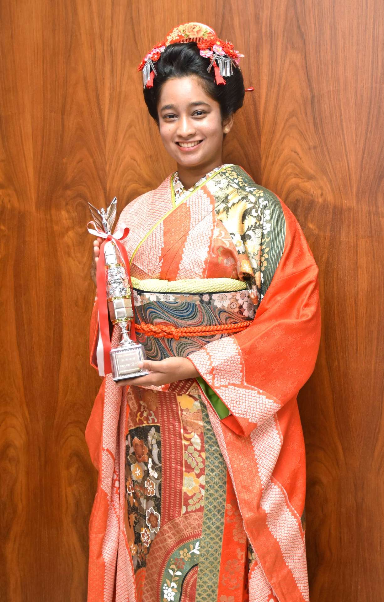 トロフィーを持ち、笑顔を見せるコディカラ・アラッチラゲ・ディルキ・プンヤジャさん＝いちき串木野市役所