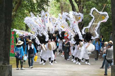 大きな矢旗を揺らしながら境内へ向かう踊り手＝２１日、日置市吹上の南方神社