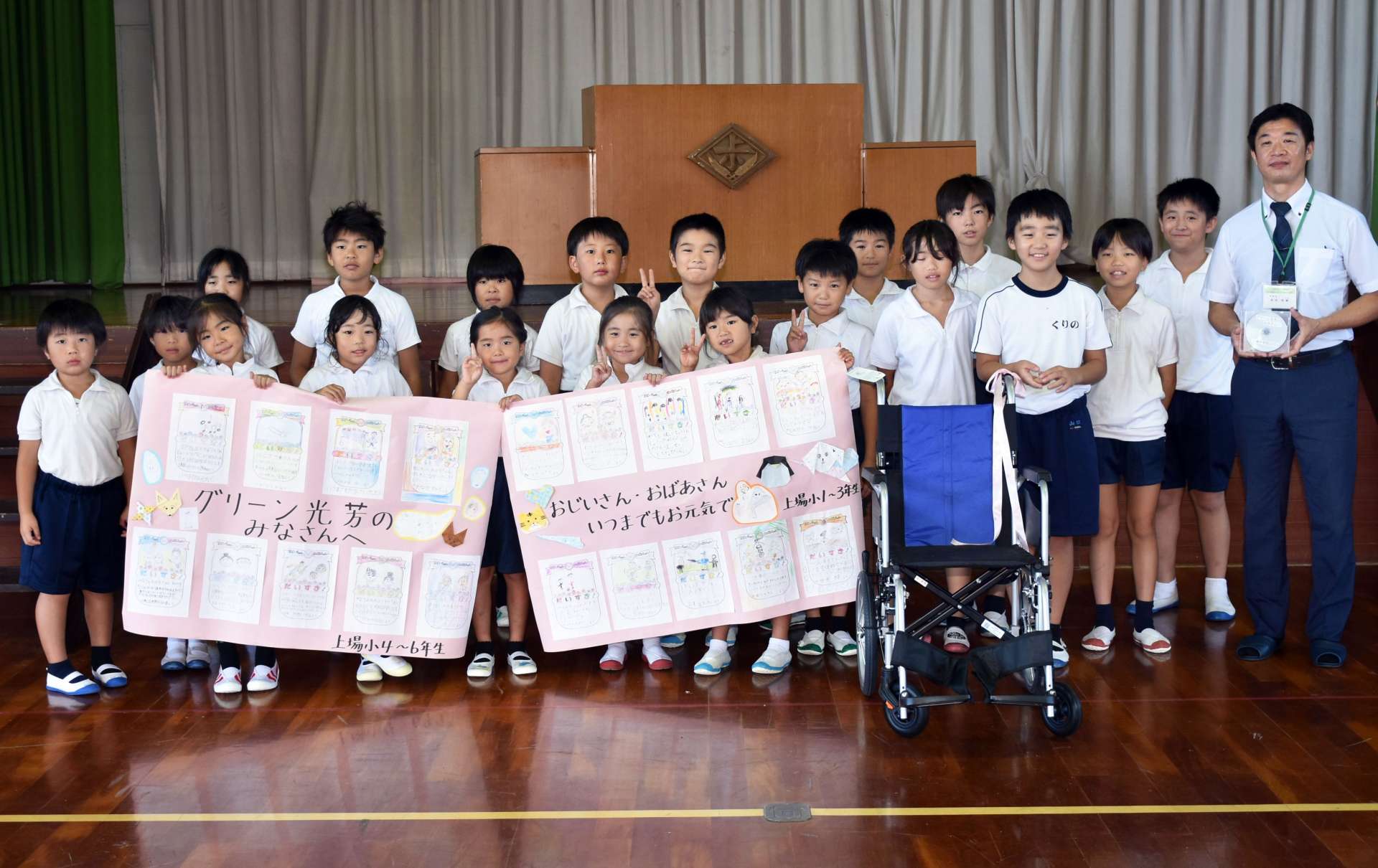 車椅子や寄せ書きなどを贈る児童ら＝湧水町の上場小学校