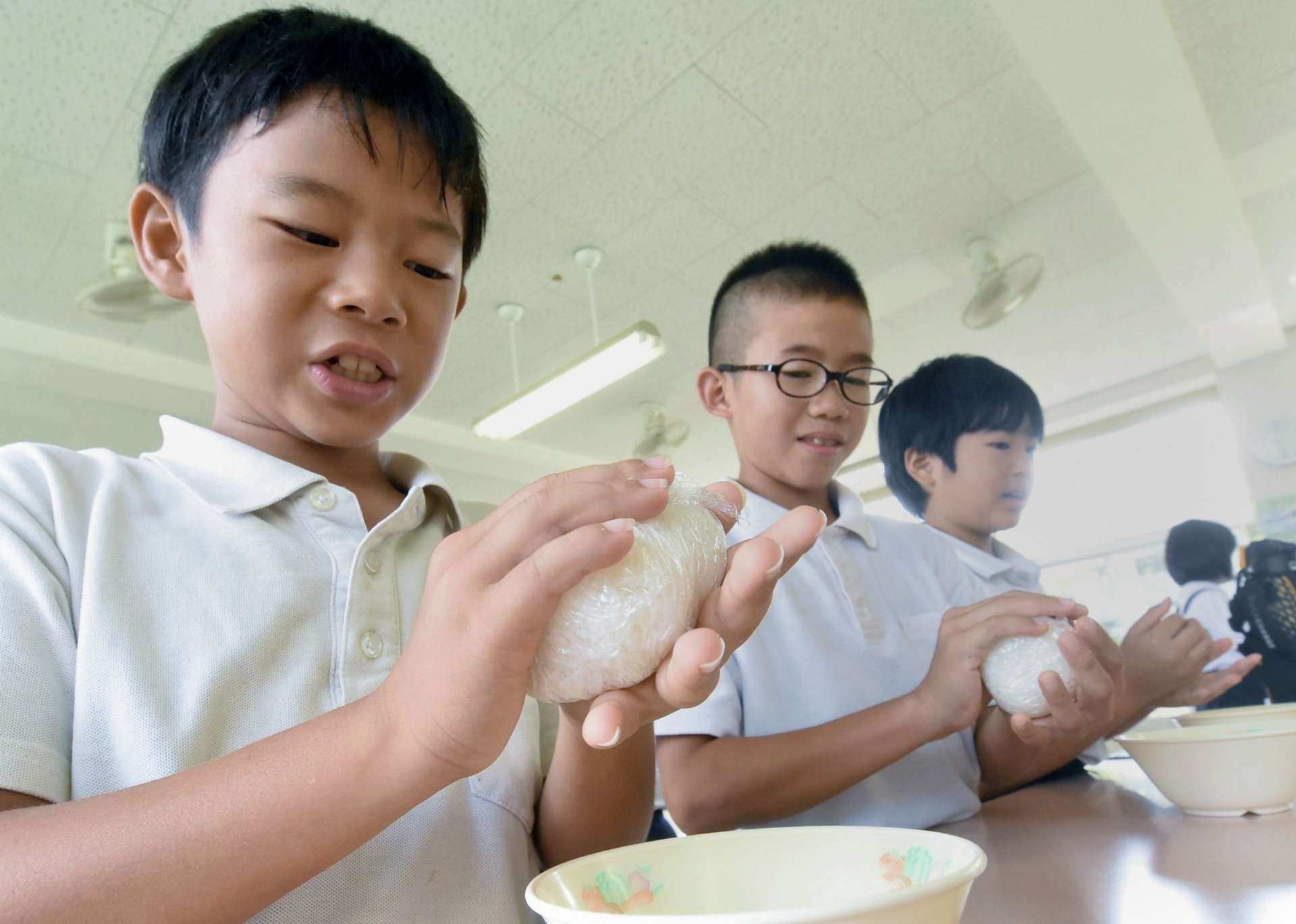 熱々の新米おにぎりを作る児童＝南さつま市の大浦小学校