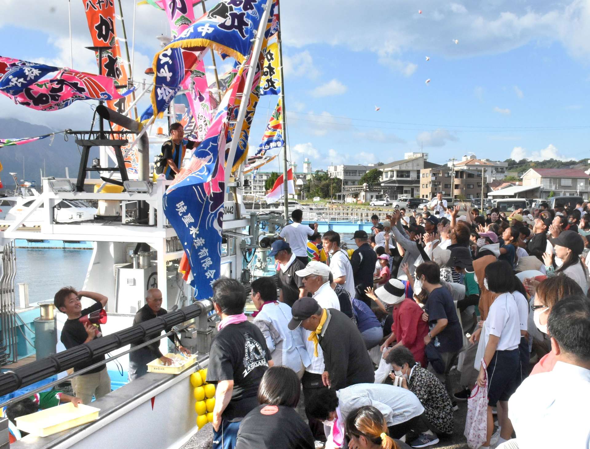 投げられる餅を求めて手を伸ばす見物客ら＝垂水市の垂水港