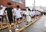 かけ声に合わせて綱を練り上げる高校生ら＝２２日、薩摩川内市の県道川内串木野線