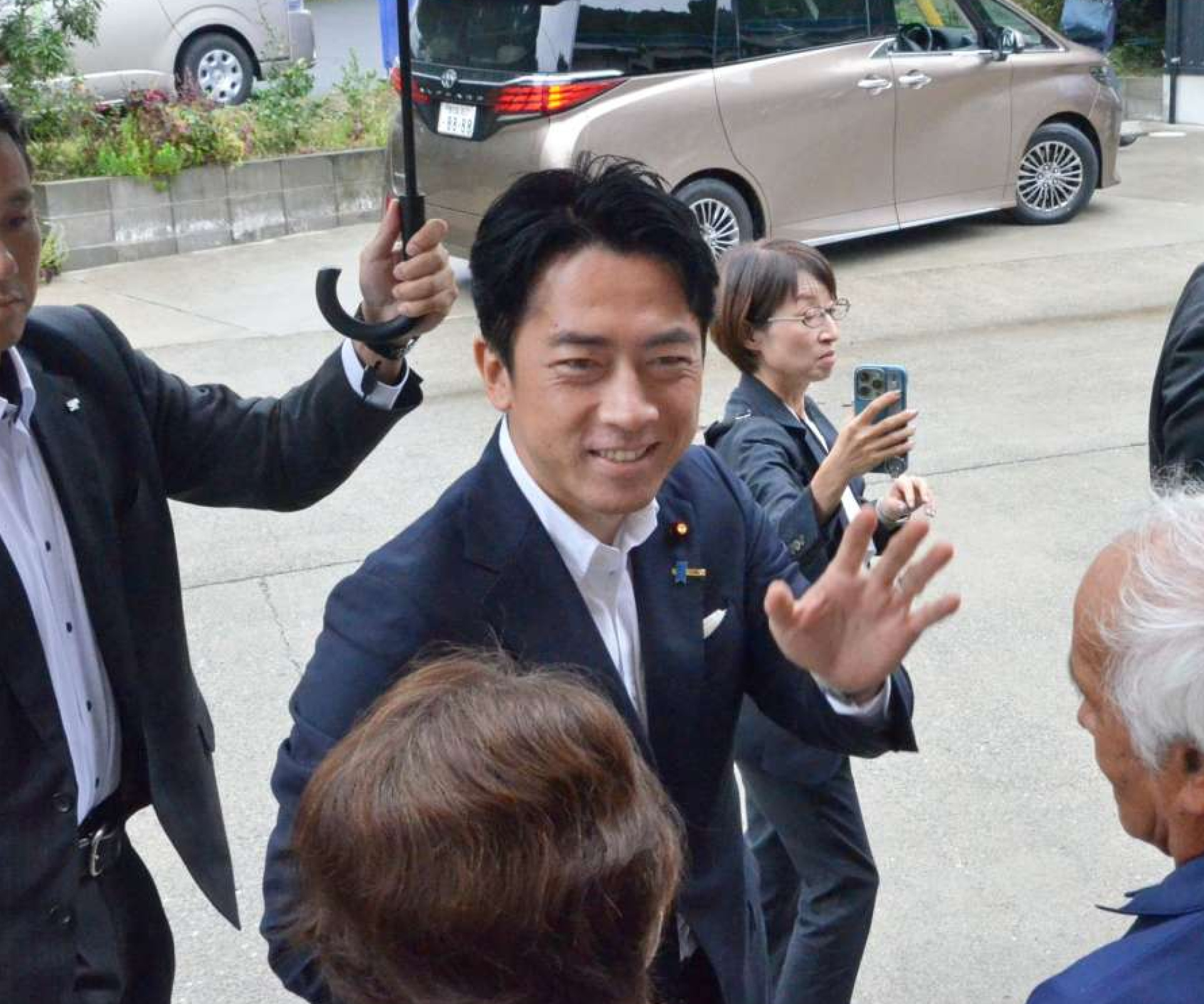 〈関連〉視察先に駆け付けた住民に笑顔で手を振る小泉進次郎氏＝２３日午前、霧島市牧園町下中津川