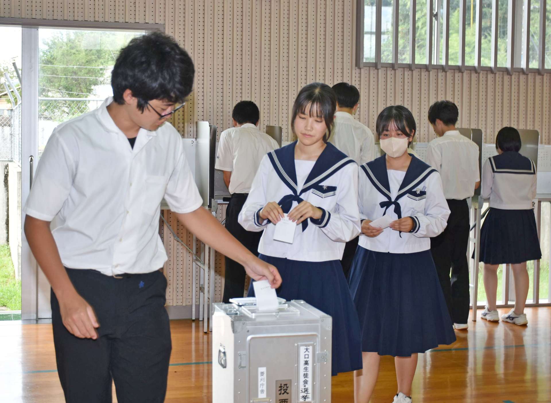 実際の公職選挙で使われる投票箱と記載台で生徒会長選挙の投票をする生徒＝伊佐市の大口高校