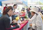 来場客に自慢の逸品を勧める出店者＝２７日、鹿児島市のＪＲ鹿児島中央駅前アミュ広場