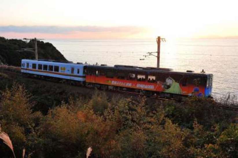 夕陽が沈む東シナ海沿いを走るおれんじ鉄道の列車（資料写真）