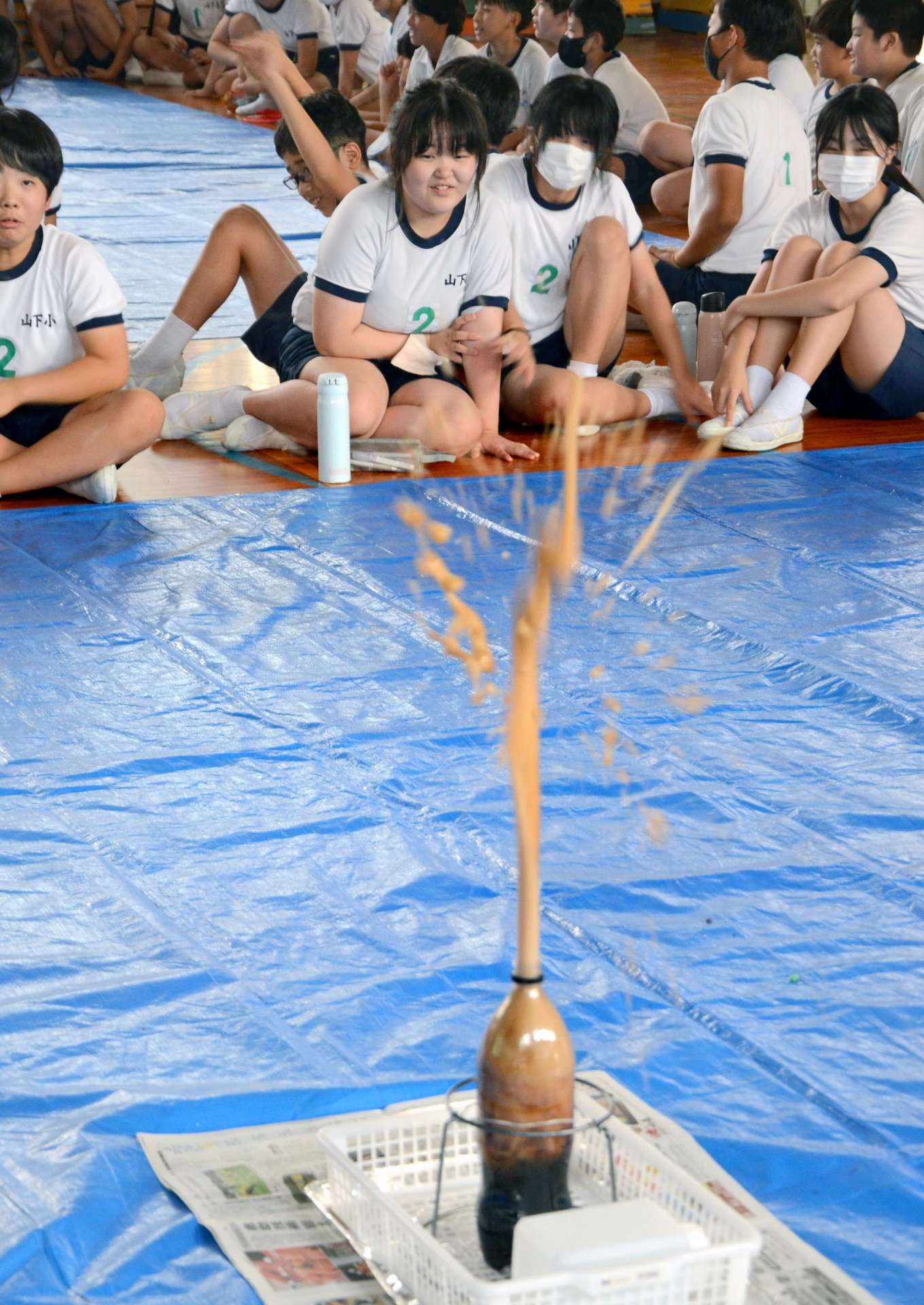 炭酸飲料を使った噴火実験を見学する児童＝２５日、鹿児島市の山下小学校