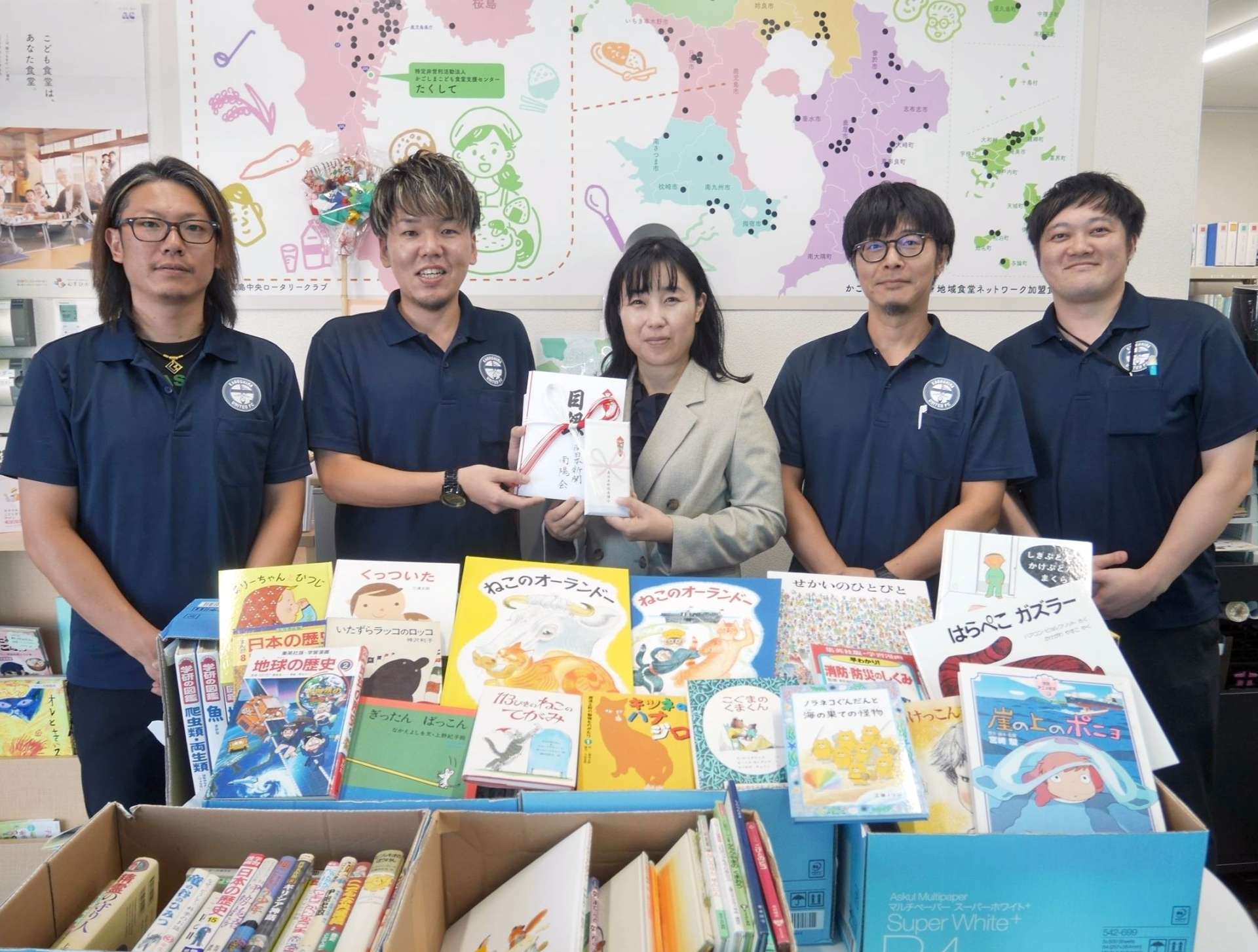 南陽会役員から目録を受け取る園田愛美代表（中央）＝２４日、鹿児島市卸本町（村山武撮影）