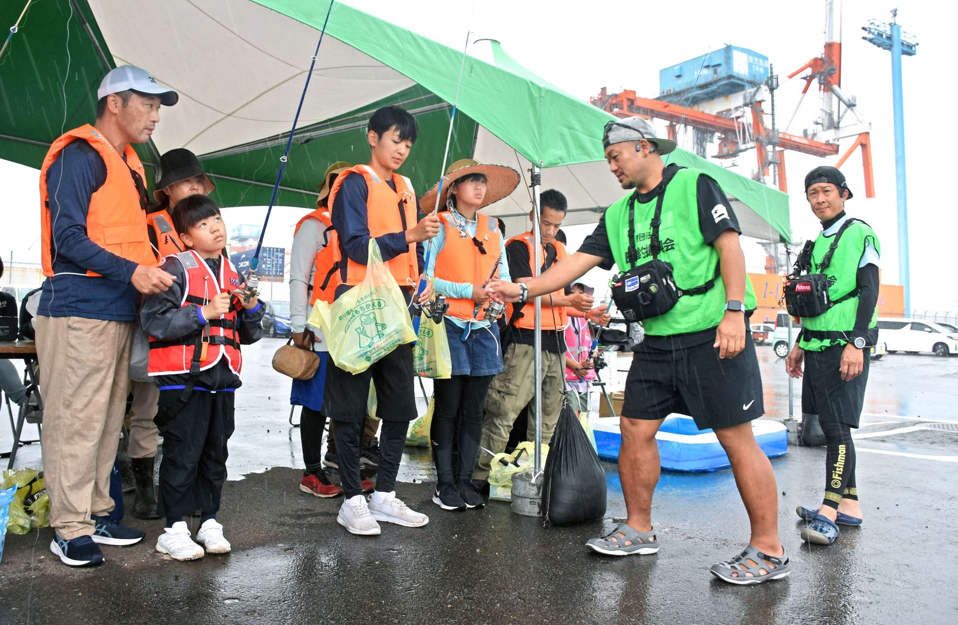 〈関連〉志布志港新若浜地区防波堤であった釣り教室に参加する家族連れ。背後にはガントリークレーンがそびえる＝志布志市志布志町安楽