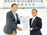 国土交通省九州地方整備局の坂井功副局長（左）から指定証を受け取る下平晴行市長＝志布志市の志布志港新若浜地区防波堤