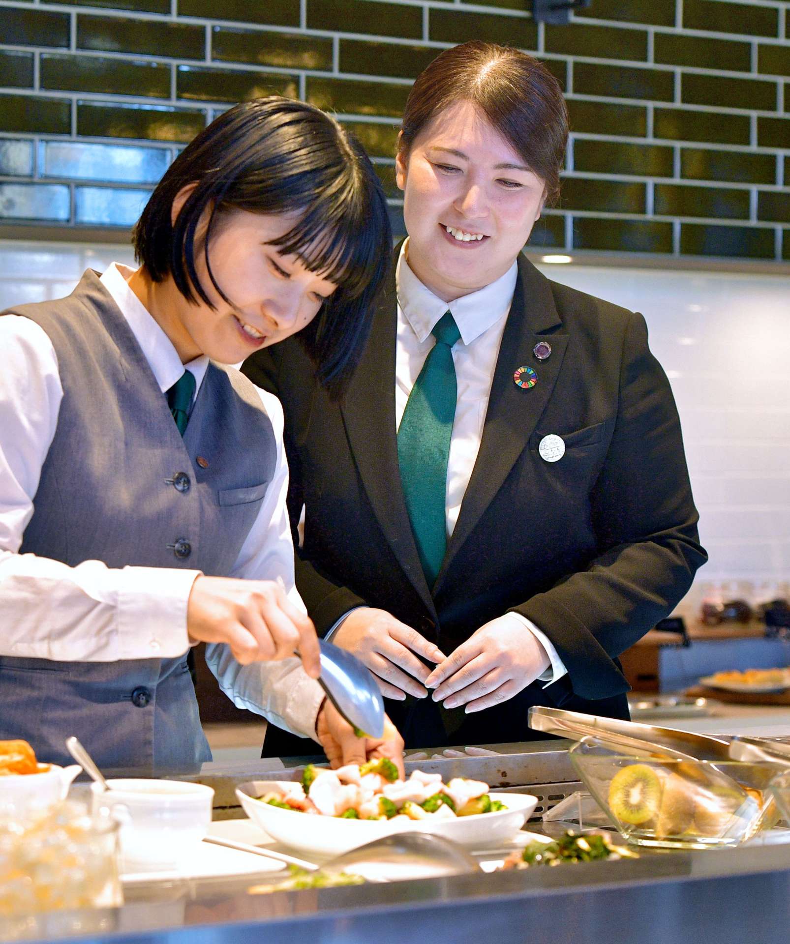 開店前準備をする後輩を見守る木下綾さん（右）＝２５日、鹿児島市の城山ホテル鹿児島