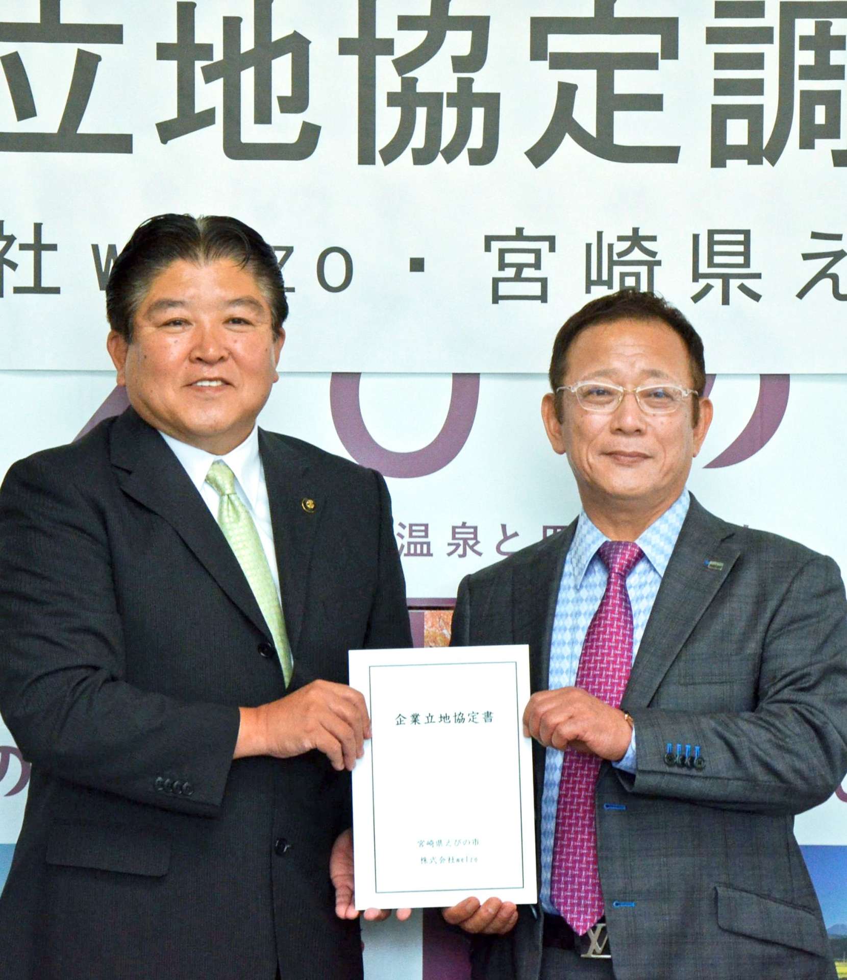 村岡隆明市長（左）と立地協定書を持つウェルゾの金尾佳文社長＝３０日、えびの市役所