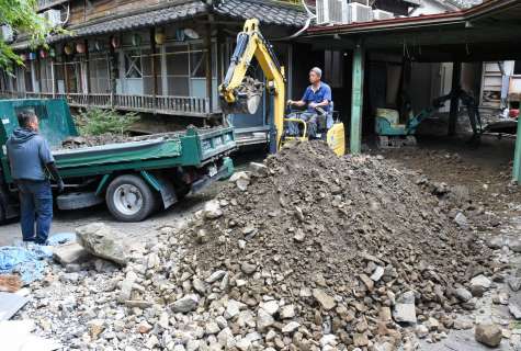 敷地に堆積した土砂などを除去する業者＝９月３０日、出水市武本の湯川内温泉かじか荘