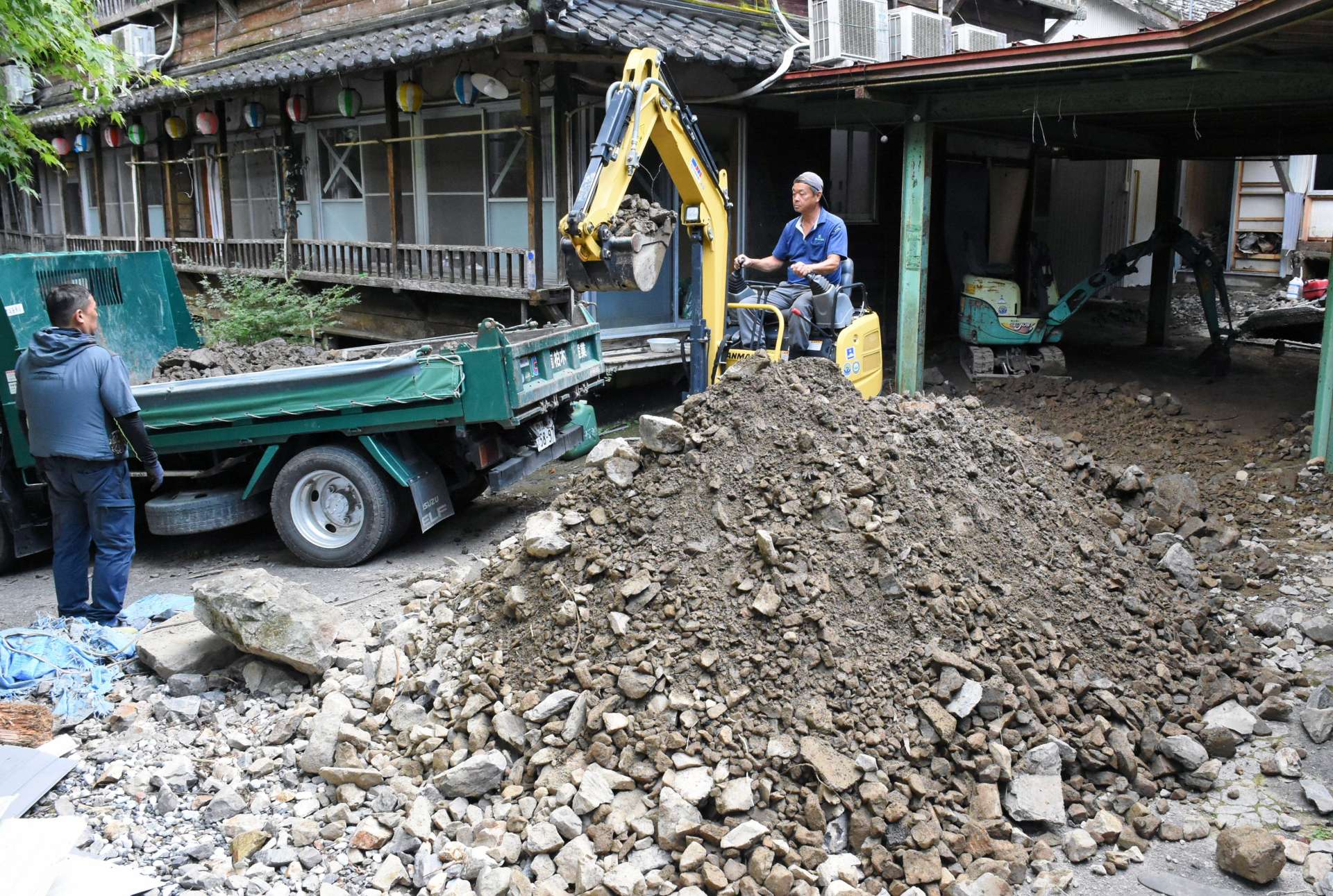 敷地に堆積した土砂などを除去する業者＝９月３０日、出水市武本の湯川内温泉かじか荘