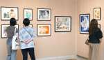 作品シリーズごとに展示された原画に見入る来場者＝鹿児島市の長島美術館