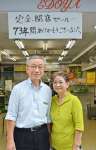 〈関連〉「７３年間ありがとうございました」という手書きの貼り紙の前で笑顔を見せる江野さん夫婦＝３日、鹿児島市東千石町の江戸屋履物店