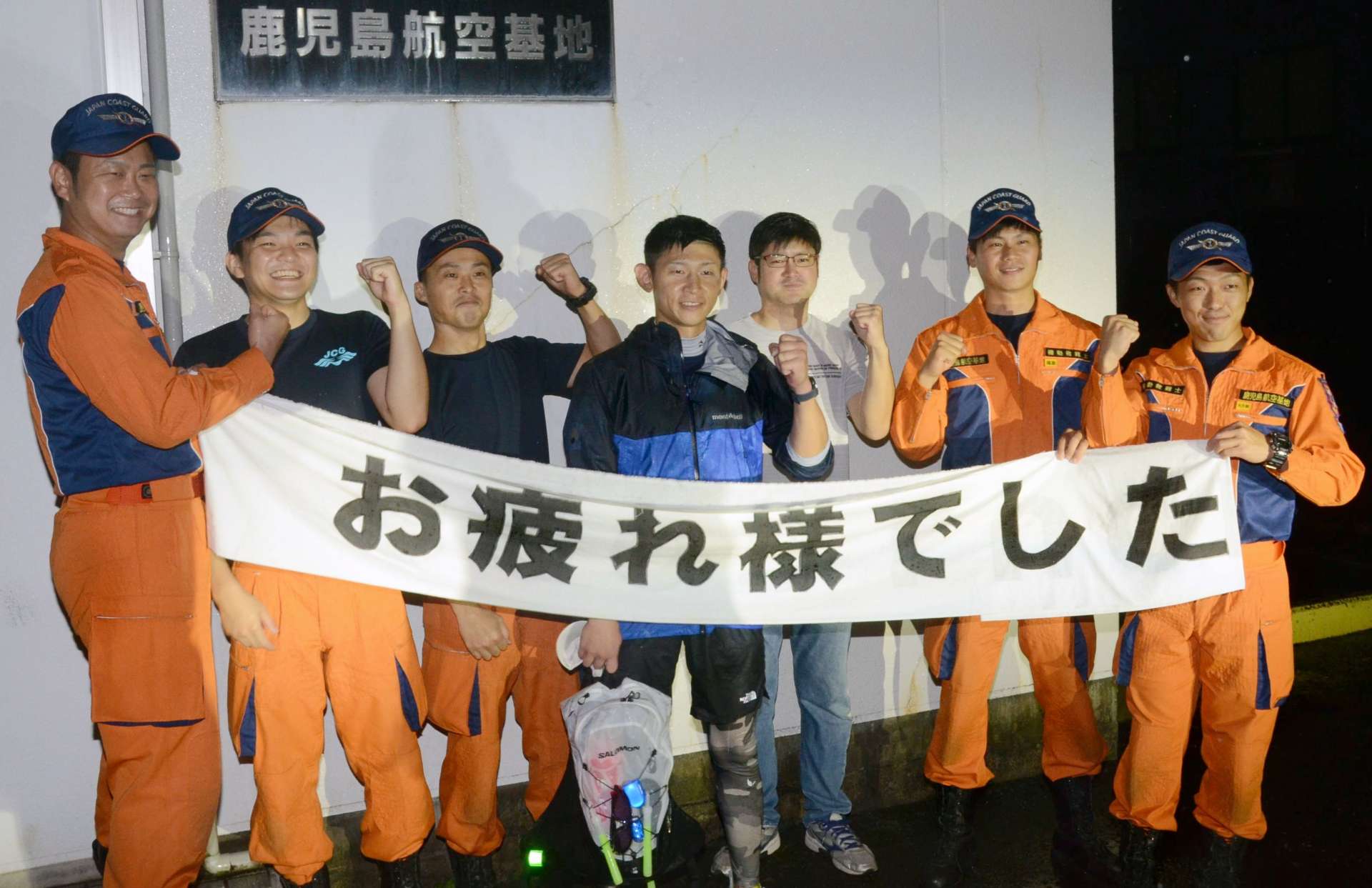 新記録でゴールした田中貫太さん（中央）とねぎらう機動救難士ら＝４日午前０時５３分、霧島市溝辺の鹿児島航空基地