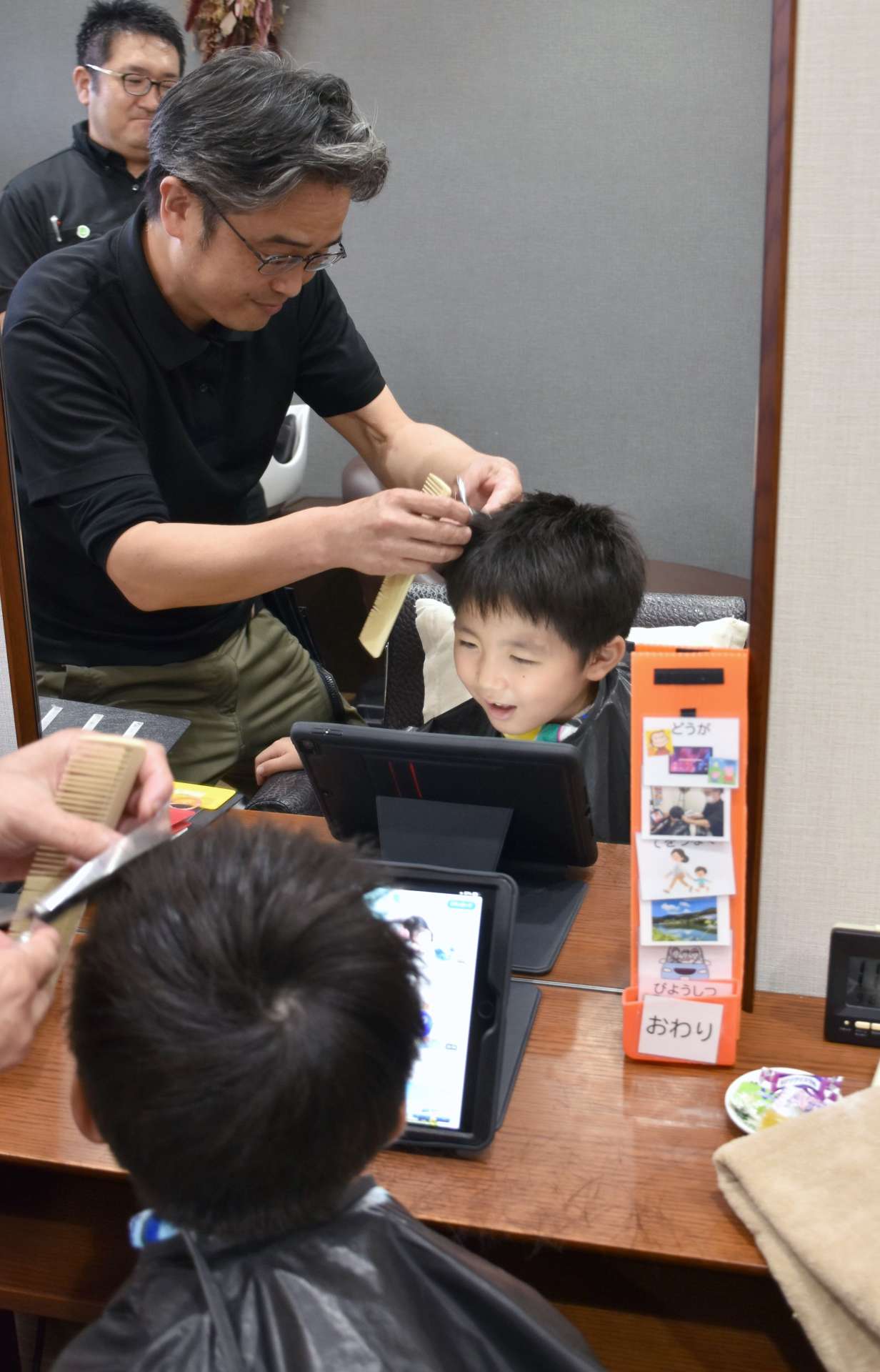 〈別カット〉頻繁に声をかけながらカットしていく廣石健一郎さん＝薩摩川内市隈之城町