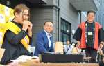 返礼品のメンチカツにかぶりつくギャル曽根さん（左）＝都城市中町