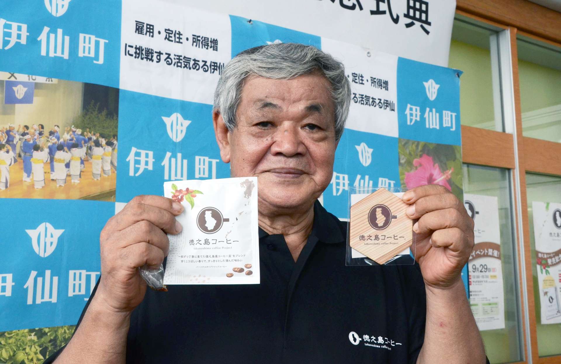 商品を手にする徳之島コーヒー生産者会の泉延吉会長＝伊仙町伊仙の特産品直売所「百菜」