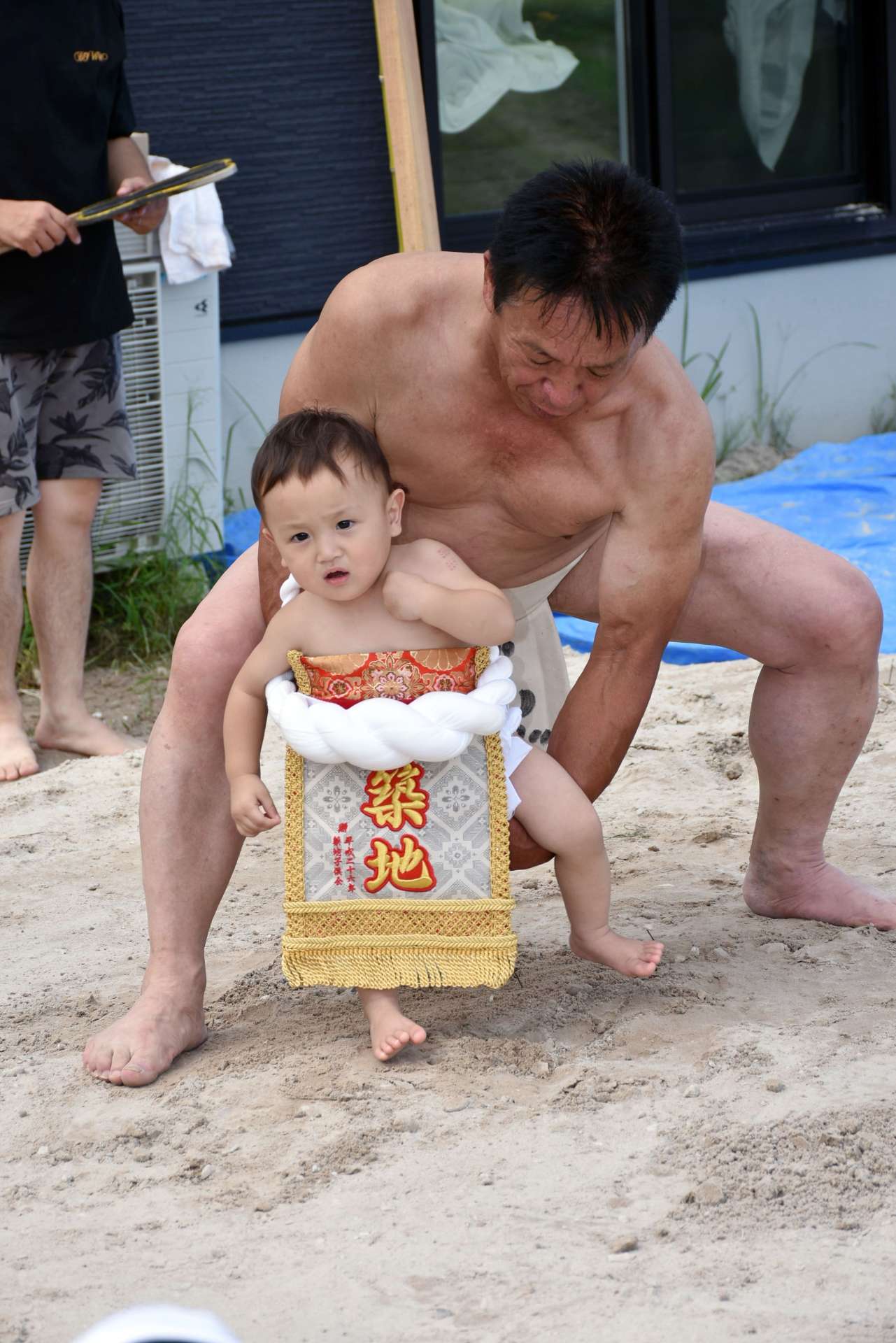 孫を抱き、赤ちゃんの土俵入りで健やかな成長を祈る橋口春男さん＝５日、伊佐市菱刈川北