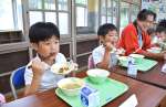 給食でマグロの揚げ煮をおいしそうに頬張る児童ら＝いちき串木野市の荒川小学校