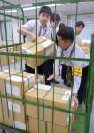 投票用紙の入った段ボール箱を運び出す職員ら＝１２日、鹿児島県庁