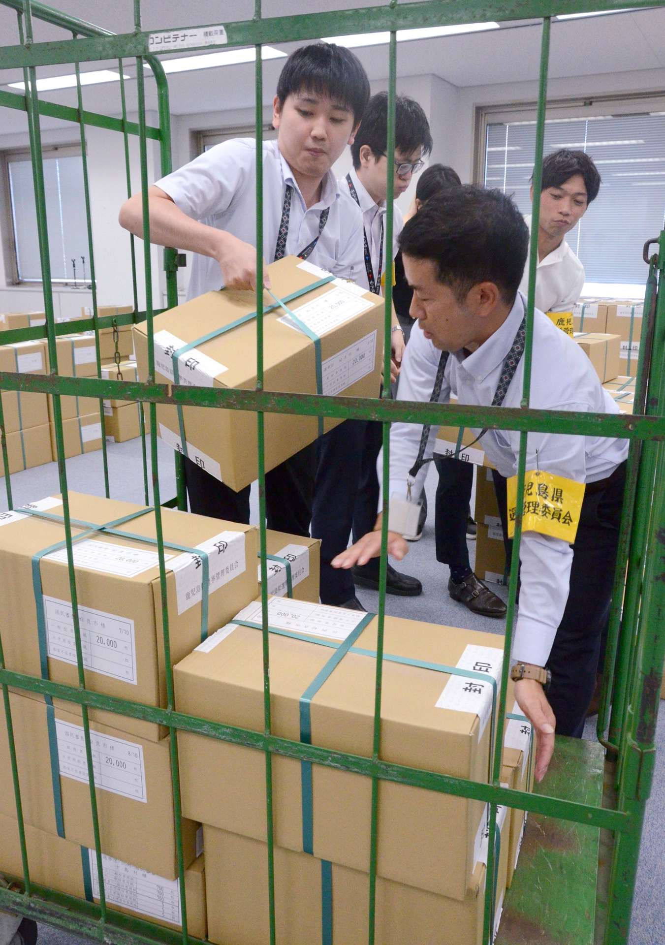 投票用紙の入った段ボール箱を運び出す職員ら＝１２日、鹿児島県庁