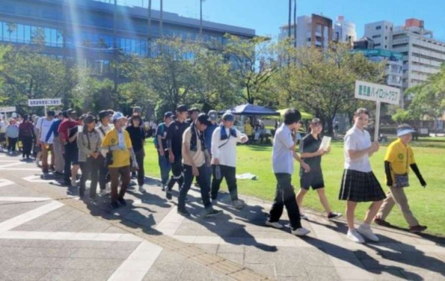 脳関連障害への理解を呼びかけて歩くパイロットウオーク参加者＝７日、鹿児島市のカクイックス交流センター前