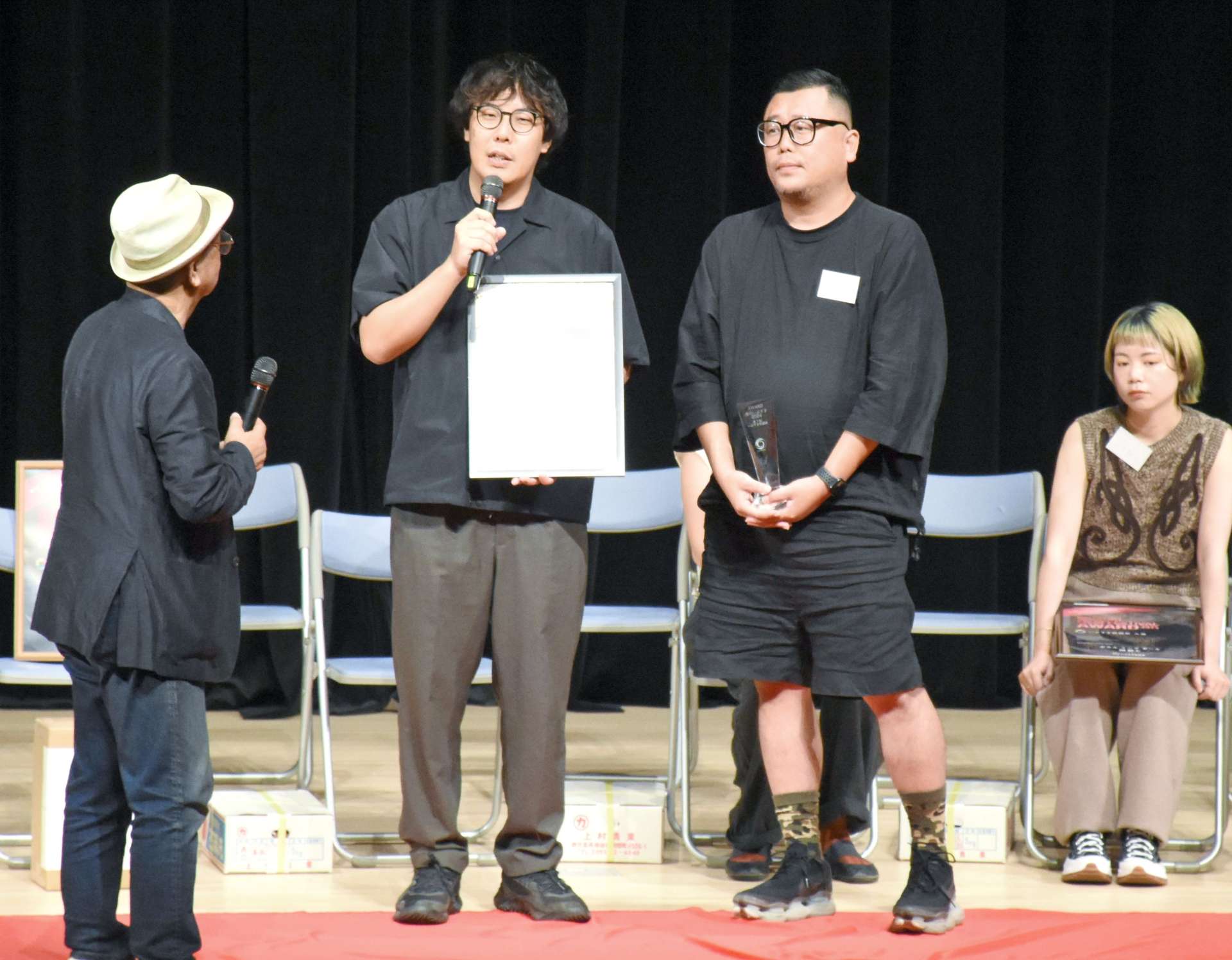来場者の投票で金のいぶすき賞に選ばれ、あいさつする眞鍋海里総監督（左）と山本ヨシヒコ監督＝指宿市民会館