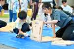 都城高専生のサポートを受け、椅子を組み立てる児童＝都城市中町の「まちなか広場」
